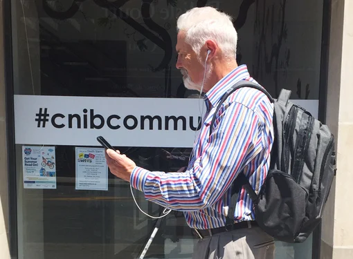 Man with vision loss uses BlindSquare Enabled Project while walking street in Toronto, Ontario