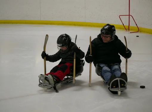 Marjorie and her son Thomas playing hockey together on an ice rink.