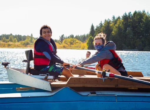 A man and a woman rowing a boat on a lake.