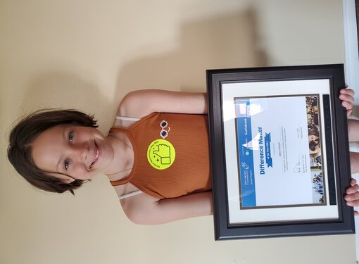 young girl holding a difference maker of the year award certificate