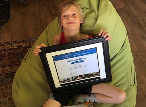 young boy with award certificate lies in a beanbag chair