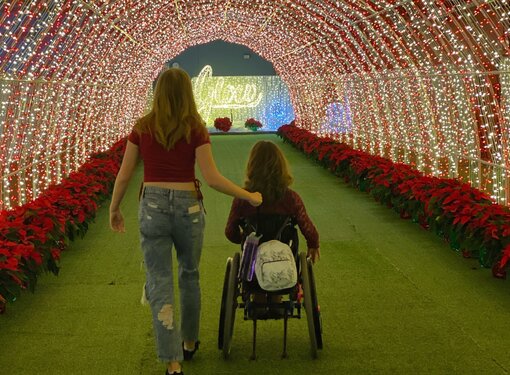 two young girls in a red and white tunnel of lights, one using a wheelchair