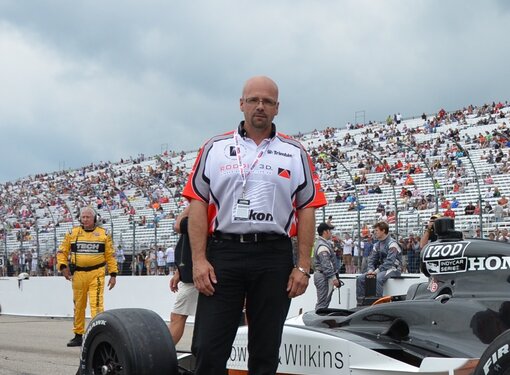 Murray Roddis standing in front of a race car on a track. 