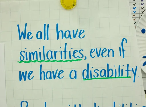 Blue ink on large paper that reads "We all have similarities, even if we have a disability." The words similarities and disability are underlined in green.