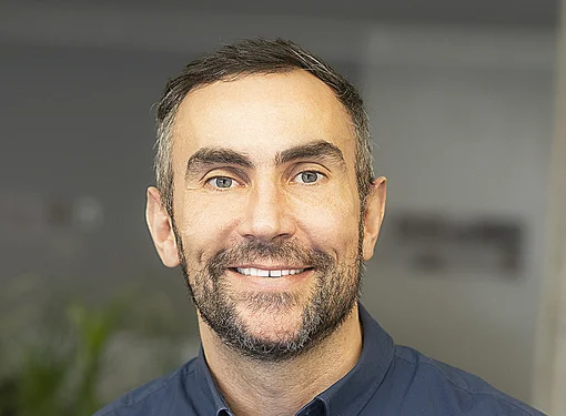 Chris Bouey smiling and wearing a blue button up shirt 