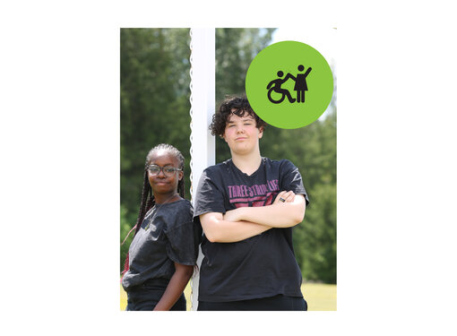 Two teenagers standing next a soccer goal post, smiling at the camera. Small green circle icon with graphic of person in a wheelchair high-fiving a person that is standing.