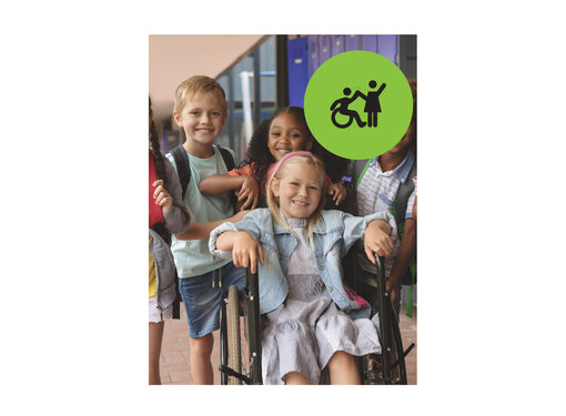 Group of young kids smiling posing for a photo at a school. One of the girls is in a wheelchair. Small green circle icon with graphic of person in a wheelchair high-fiving a person that is standing.