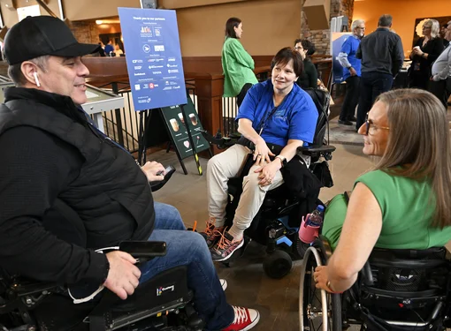 Three people who are using wheelchairs having a conversation at a conference. 