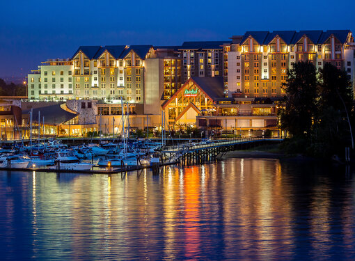 Building on the water lit up at night with boats in the foreground 