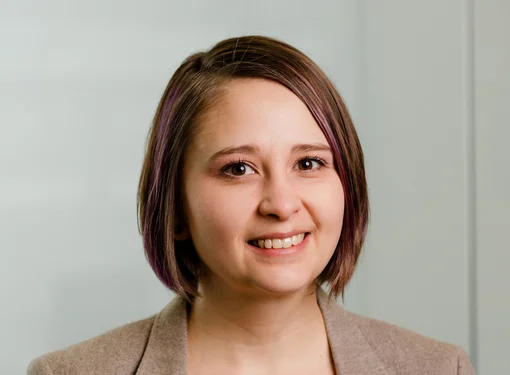 Sherry Hastings, who has chin-length brown hair and brown eyes. She is wearing a beige blazer and standing in front of a cream-coloured wall.