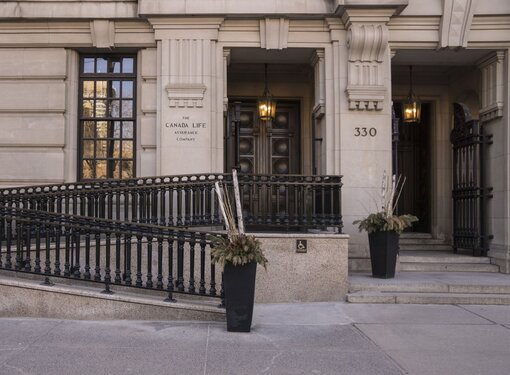 Accessible ramp with ornate metal railing at exterior entrance of Canada Life offices in London, Ontario.