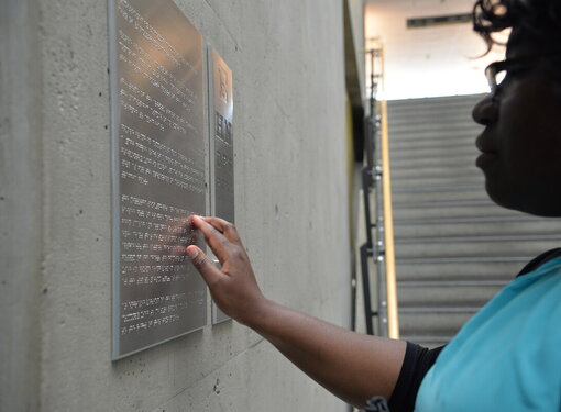 an image of an individual reading a braille sign on a wall 