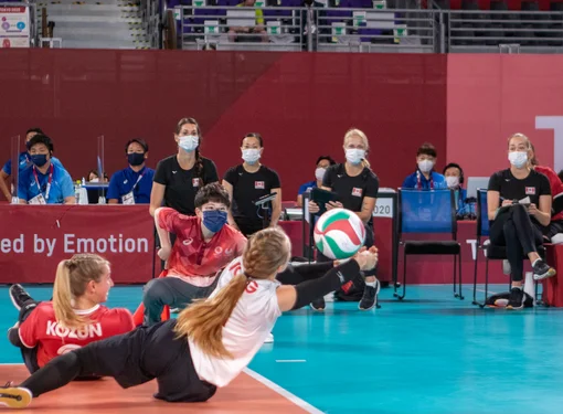 Jolan Wong playing sitting volleyball for Team Canada. She is diving for the ball.