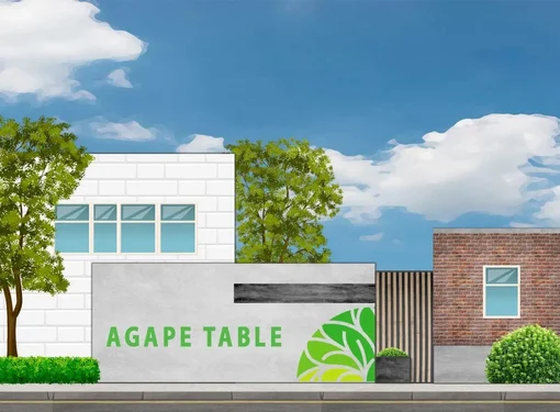 Rendering of three buildings: The small center one has a sign reading ‘Agape Table’. The left building is white with a colorful mural. Trees and a blue sky frame the scene.