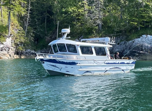 A boat on the water with a person fishing at the back, surrounded by nature in the background