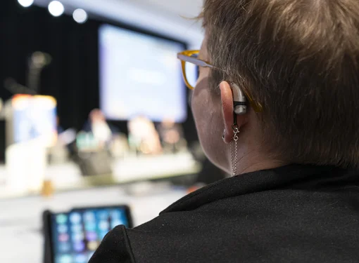 Rear view of a woman with a visible hearing aid behind her ear