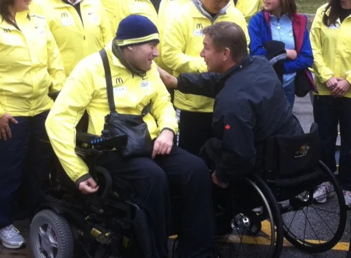 People around two men in wheelchairs talking to each other