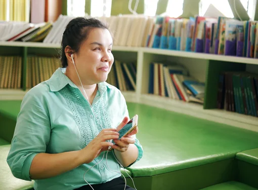 Woman who is blind using headphones to listen to a mobile phone