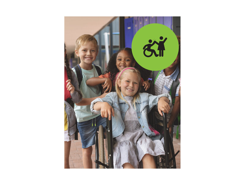 Group of young kids smiling posing for a photo at a school. One of the girls is in a wheelchair. Small green circle icon with graphic of person in a wheelchair high-fiving a person that is standing.