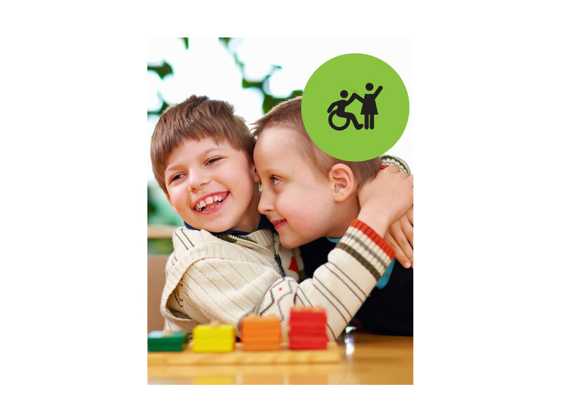 Two boys playing with coloured blocks. One boy has his arms around the other boys's shoulders. Small green circle icon with graphic of person in a wheelchair high-fiving a person that is standing.