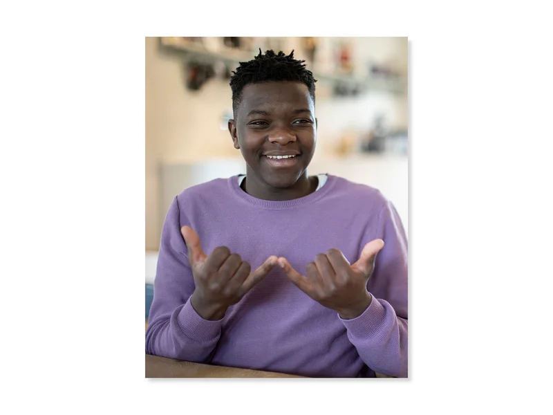 Teen wearing purple long sleeve shirt, signing in American Sign Language.
