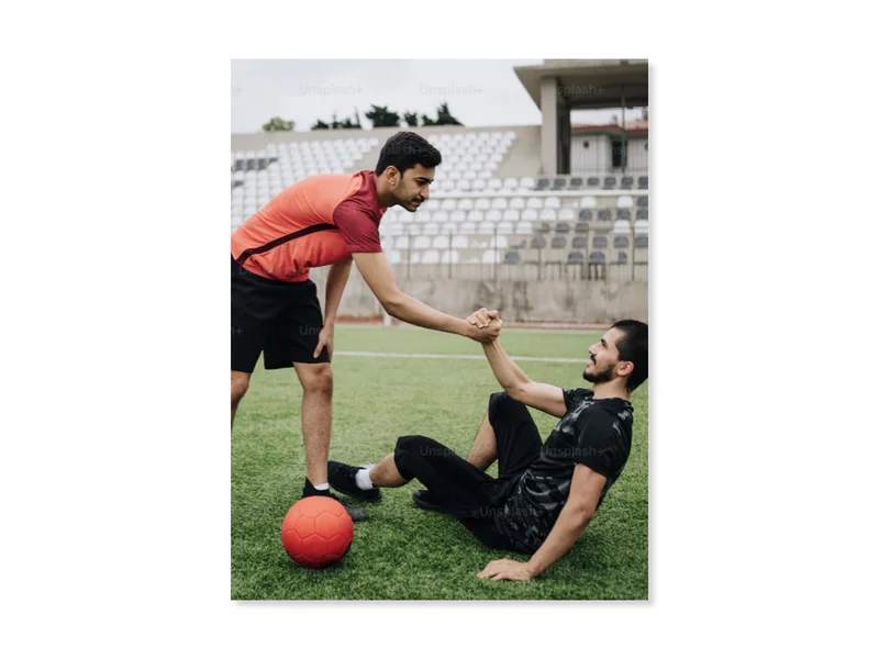 Two young men on a soccer field, shaking hands and showing fair play.