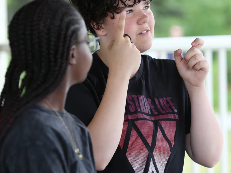 Two young individuals communicating with each other using sign language