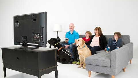 A family, and guide dog, watching television Thumbnail