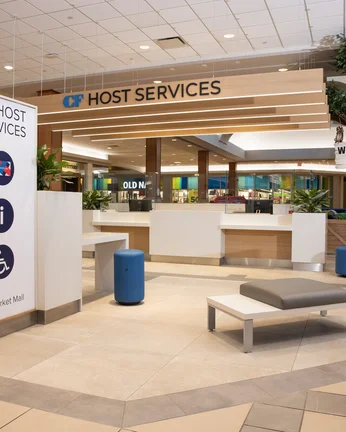 A wide corridor leads to a lowered desk with a sign above that says host services