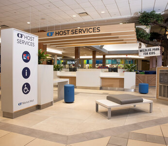 A wide corridor leads to a lowered desk with a sign above that says host services