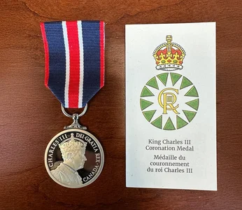 A commemerative medal on a wood table with the text: King Charles Coronation Medal