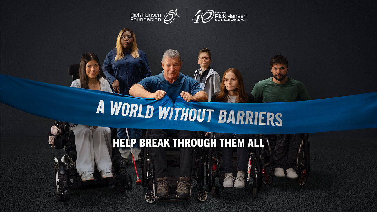 six people with visible mobility, vision, and hearing accessibility tools, including wheelchairs, a power wheelchair, a white cane, and hearing technology. A person at the centre grips a large blue banner reading “A World Without Barriers.” The Rick Hansen Foundation and 40th Anniversary Man In Motion World Tour logos appear above, with the text “Help Break Through Them All” below.
