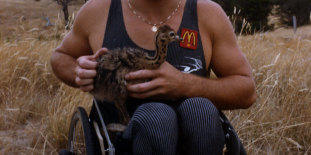 Rick Hansen holding a baby ostrich in New Zealand during January of 1986