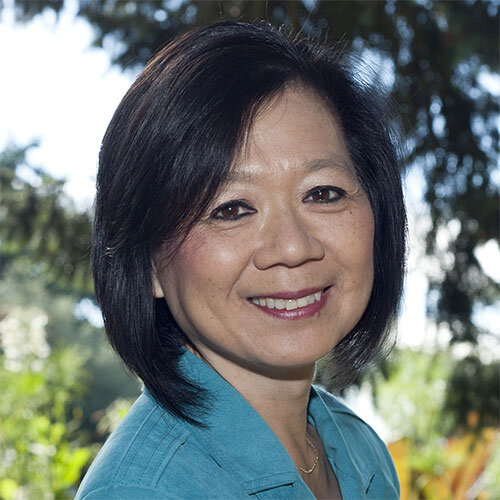 Middle aged woman with black short hair, brown eyes, wearing turquoise blouse. 