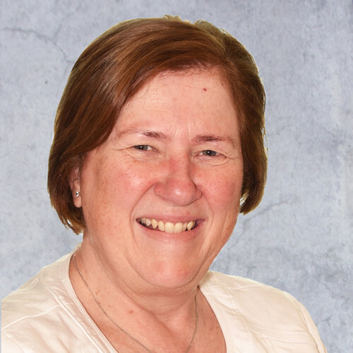 Woman with short brown hair, smiling, wearing a white blouse