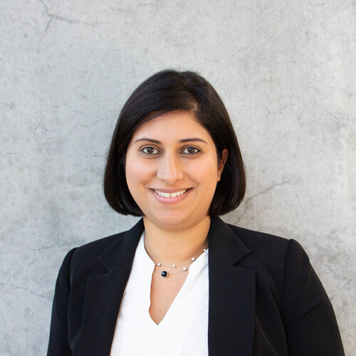  Woman with brown short hair, brown eyes, smiling wearing a black blazer with white shirt. 