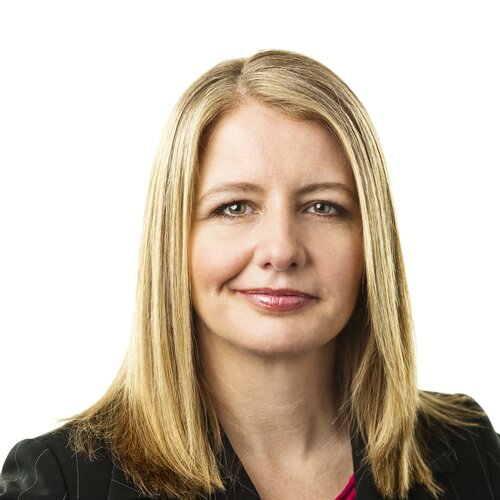 Women with medium blonde hair, brown eyes, smiling wearing black blazer. 