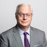 Headshot, man in suit and glasses, smiling