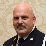 Middle aged man, bald, smiling, wearing work uniform. 