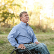 man with wheelchair outdoors, wearing professional attire
