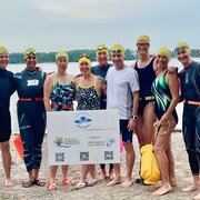 group of swimmers holding a big cheque with the RHF logo